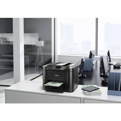 Ein Drucker auf einem modernen Büroschreibtisch druckt farbige Dokumente. Im Hintergrund sind Computerarbeitsplätze sichtbar.