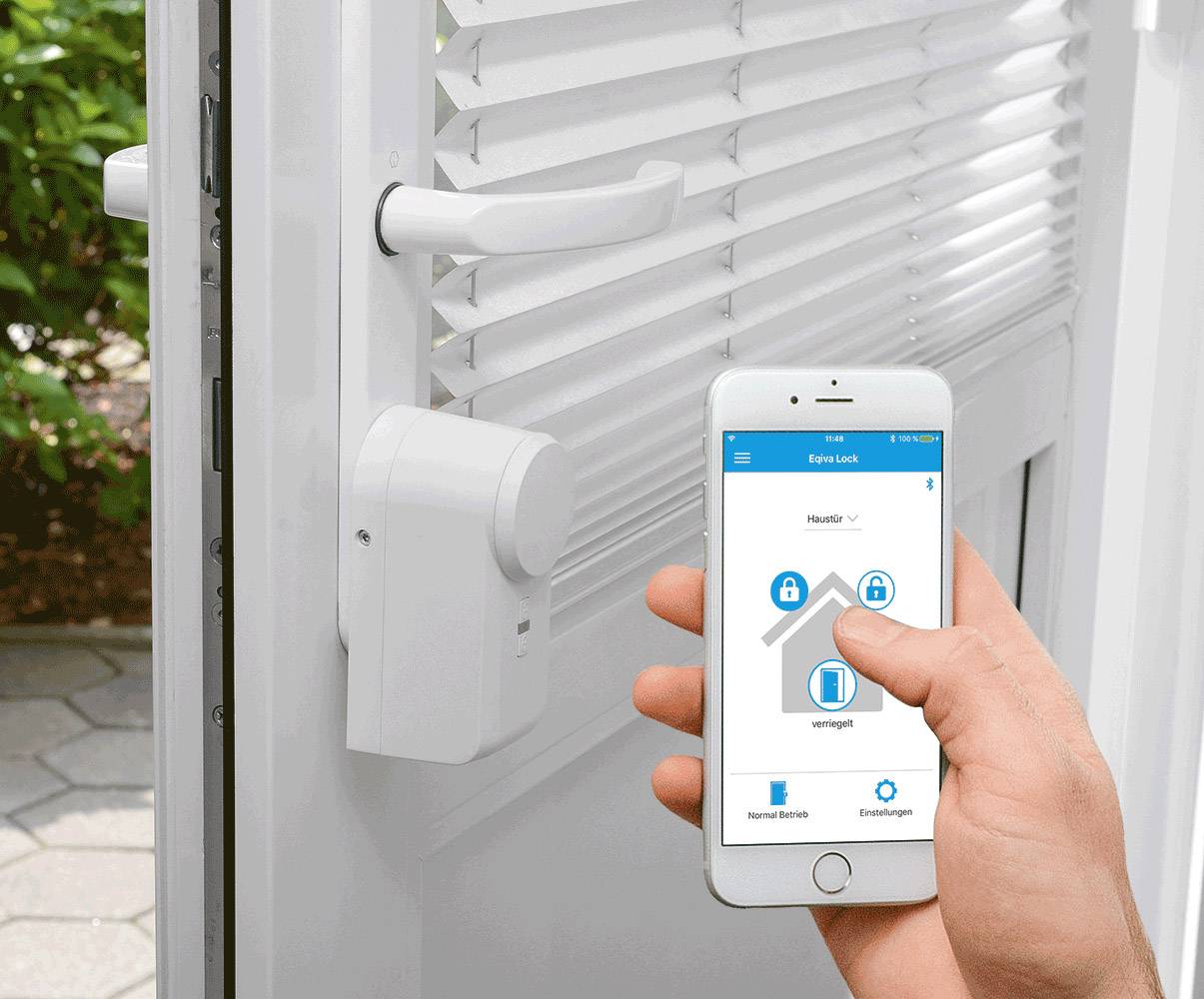 Eine Person bedient eine Smart-Home-App auf einem Smartphone, um ein elektronisches Türschloss an einer weißen Tür zu steuern.