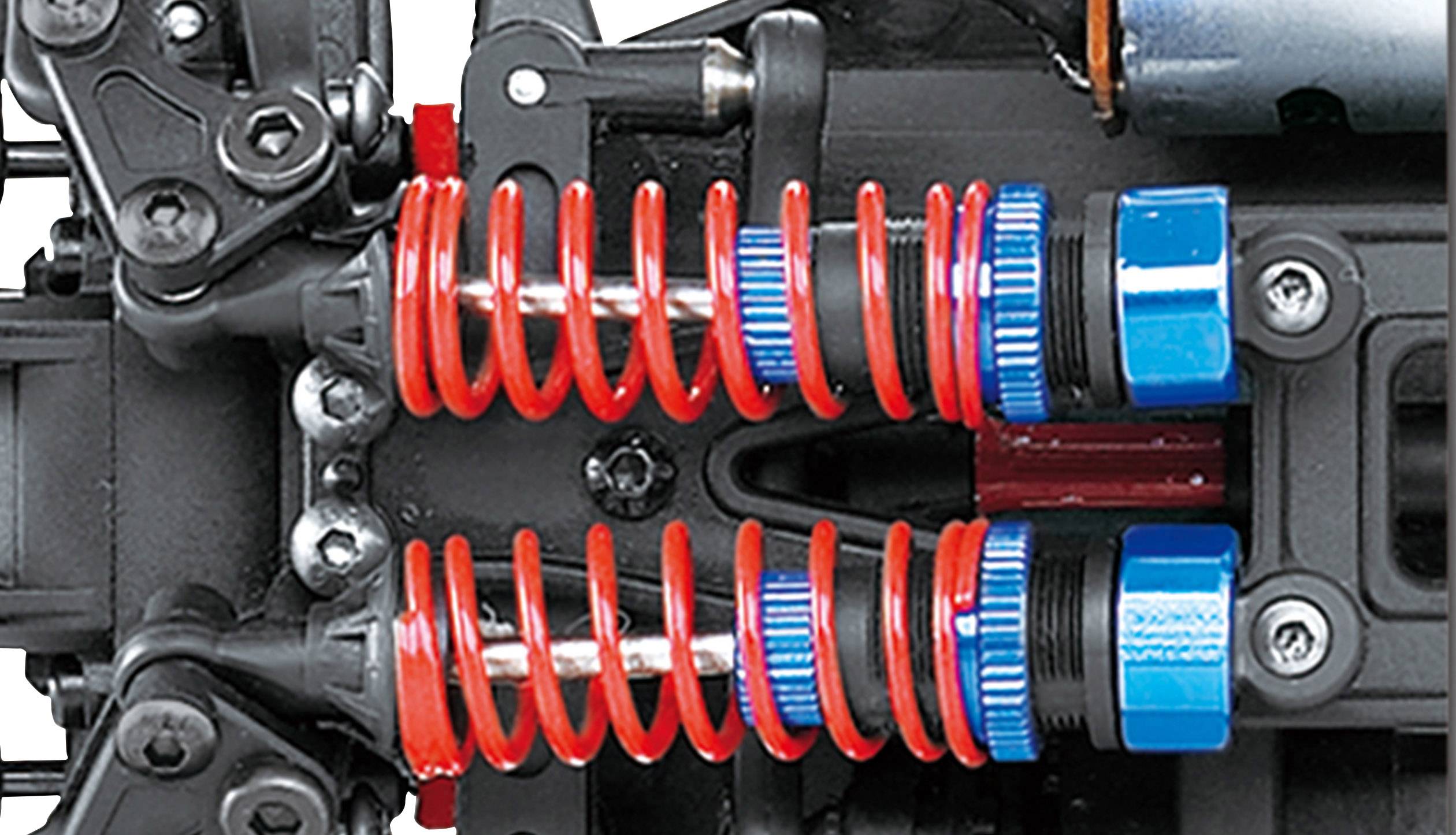 Nahaufnahme eines Federungssystems eines Fahrzeugs, das rote Spiralfedern und blaue Stoßdämpfer zeigt, montiert an einer schwarzen Metallstruktur.
