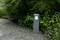 Außenleuchte auf einem Kiesweg, umgeben von grünen Pflanzen, spendet Licht in einem Gartenbereich.