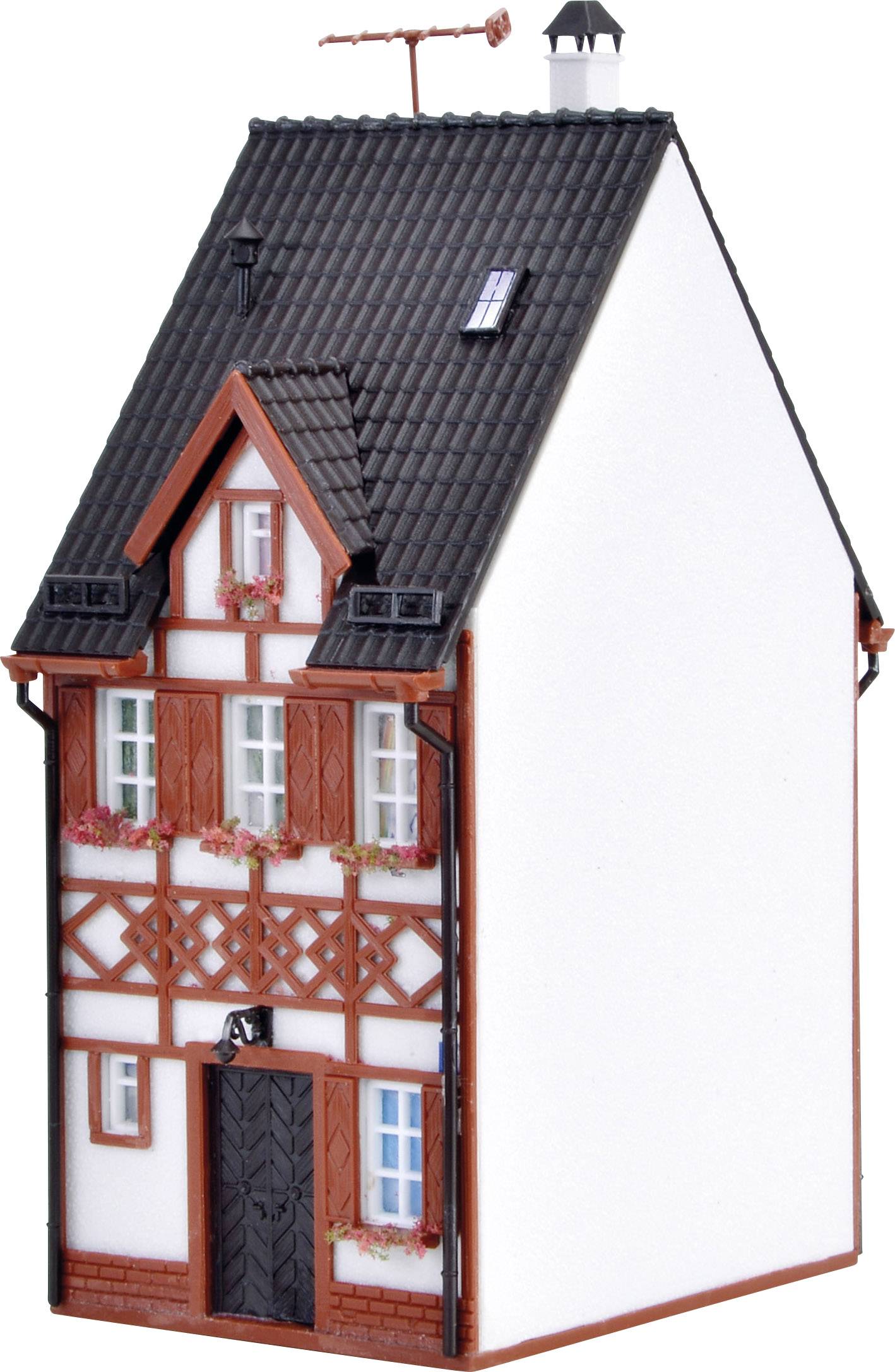 Kleines Fachwerkhausmodell mit schwarzem Dach, Blumen an den Fenstern und hölzernen Verzierungen an der Fassade.