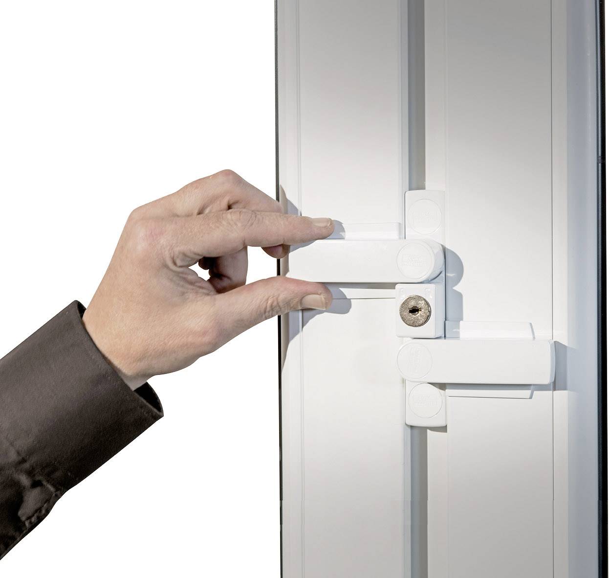 Hand öffnet weißen Sicherheitsriegel an einer weißen Tür, zeigt Funktionsweise eines Verriegelungssystems.