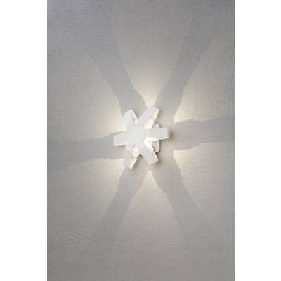 Weiße Wandlampe mit strahlenförmigem Design wirft ein sternförmiges Muster aus Lichtstrahlen auf die graue Wand.