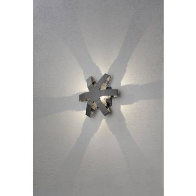 Wandleuchte mit modernem Design, wirft symmetrische Licht- und Schattenmuster in Sternform an die Wand.