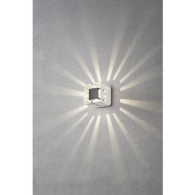 Ein Wandlicht strahlt symmetrische Lichtstrahlen ab, die an eine Sonne erinnern. Die Lampe ist in einem modernen Design an der grauen Wand montiert.