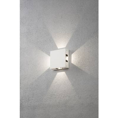 Eine quadratische, weiße Wandleuchte an einer grauen Wand, die in einem dekorativen Muster Licht nach oben und unten abstrahlt.