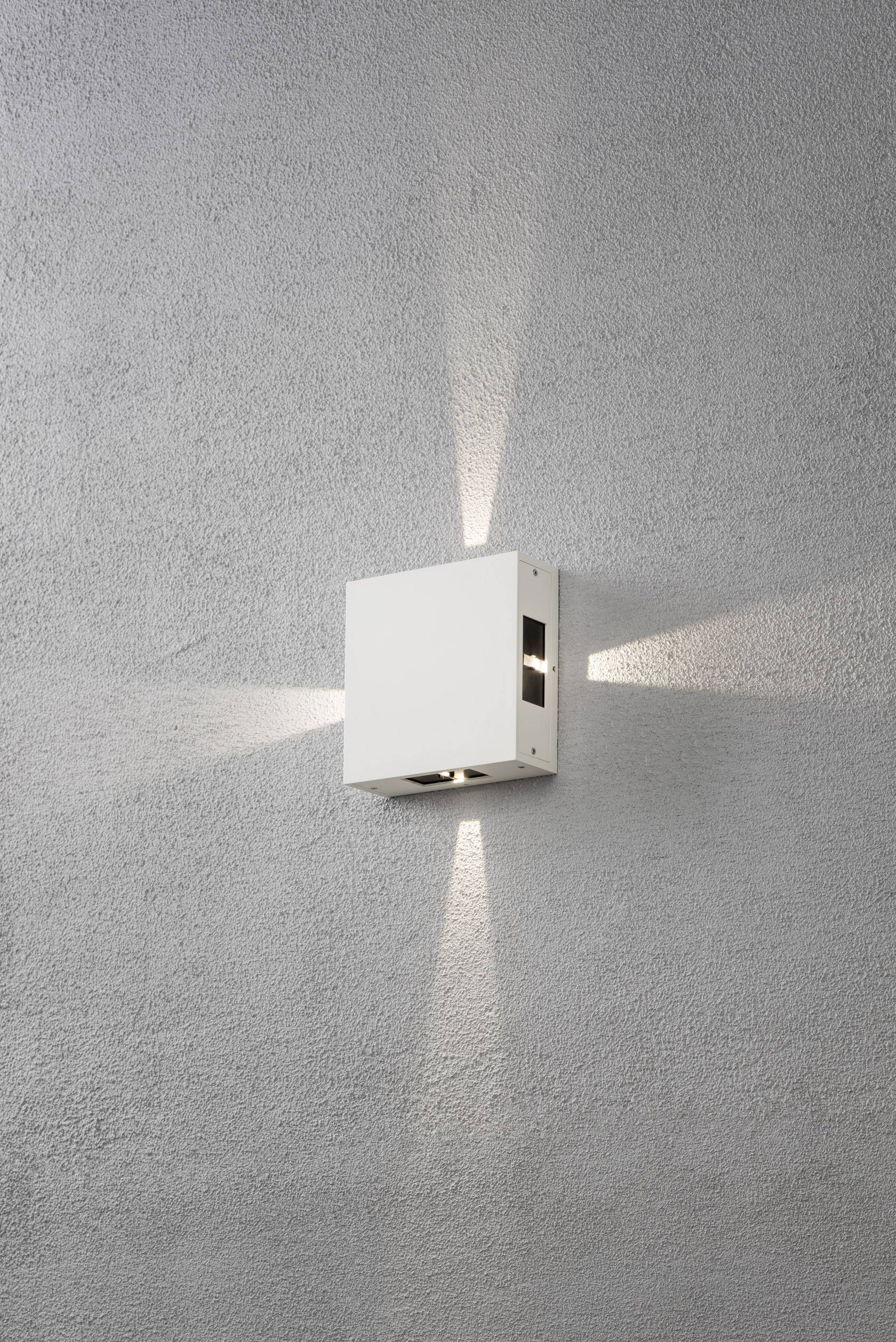 Weiße Wandleuchte strahlt Licht nach oben und unten auf graue Wand, erzeugt geometrisches Muster. Modernes, minimalistisches Design.