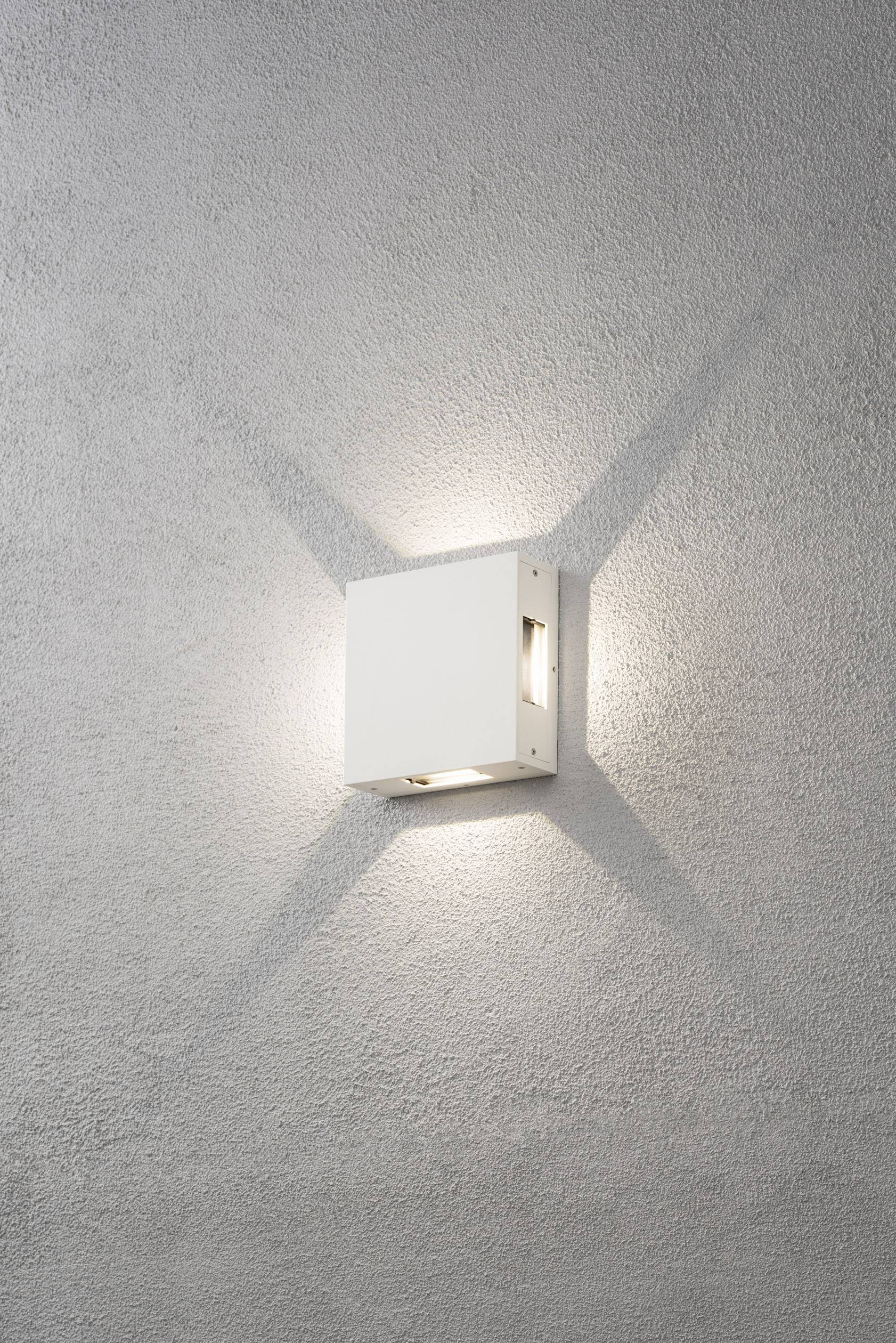 Weiße, quadratische Wandleuchte leuchtet nach oben und unten auf einer grauen Wand. Schritteffekt sichtbar durch Lichtstrahlen.