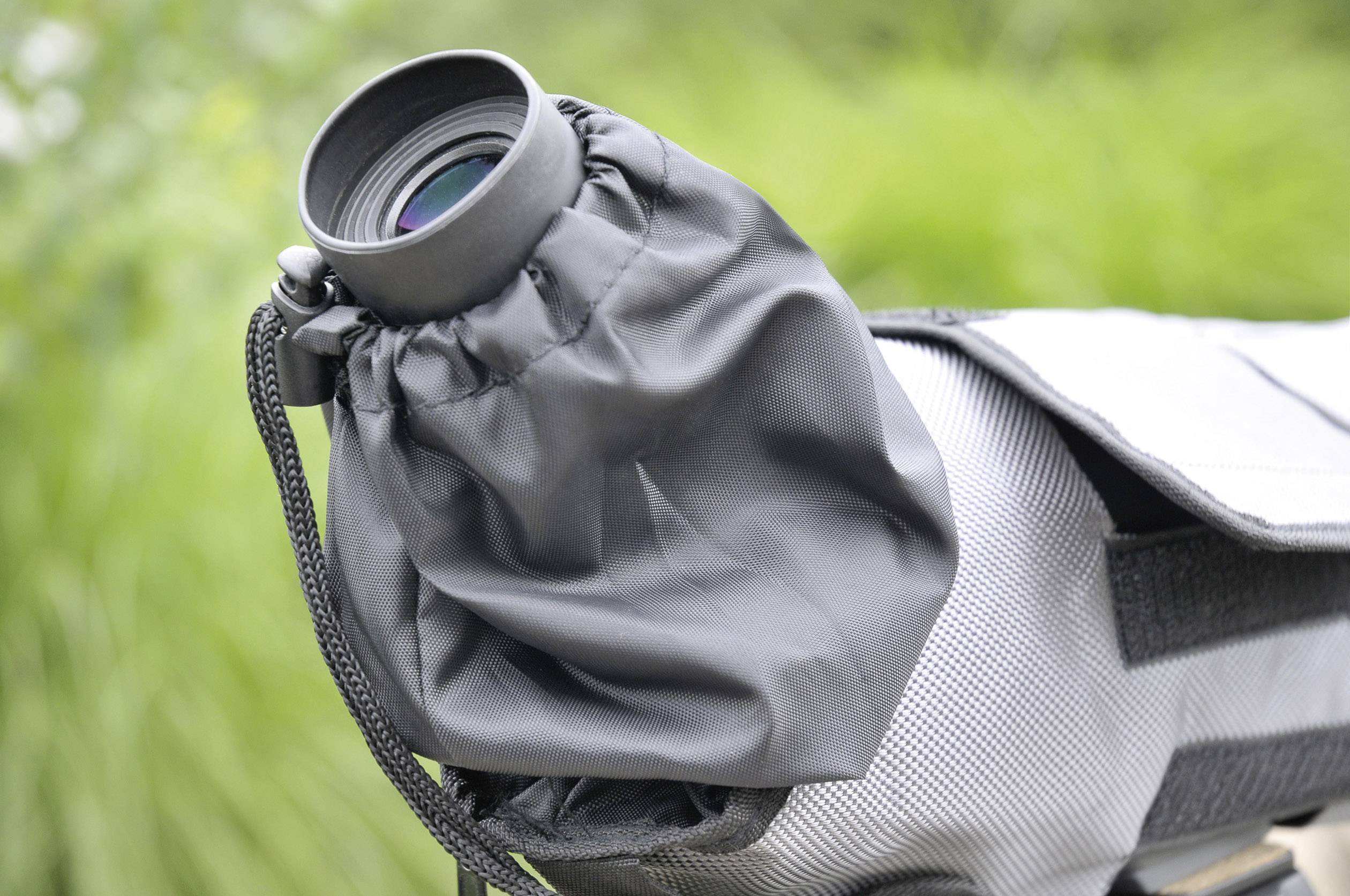 Ein Fernglas geschützt von einem wetterfesten Schutzüberzug. Im Hintergrund unscharfes Grün, das auf eine Naturumgebung hindeutet.