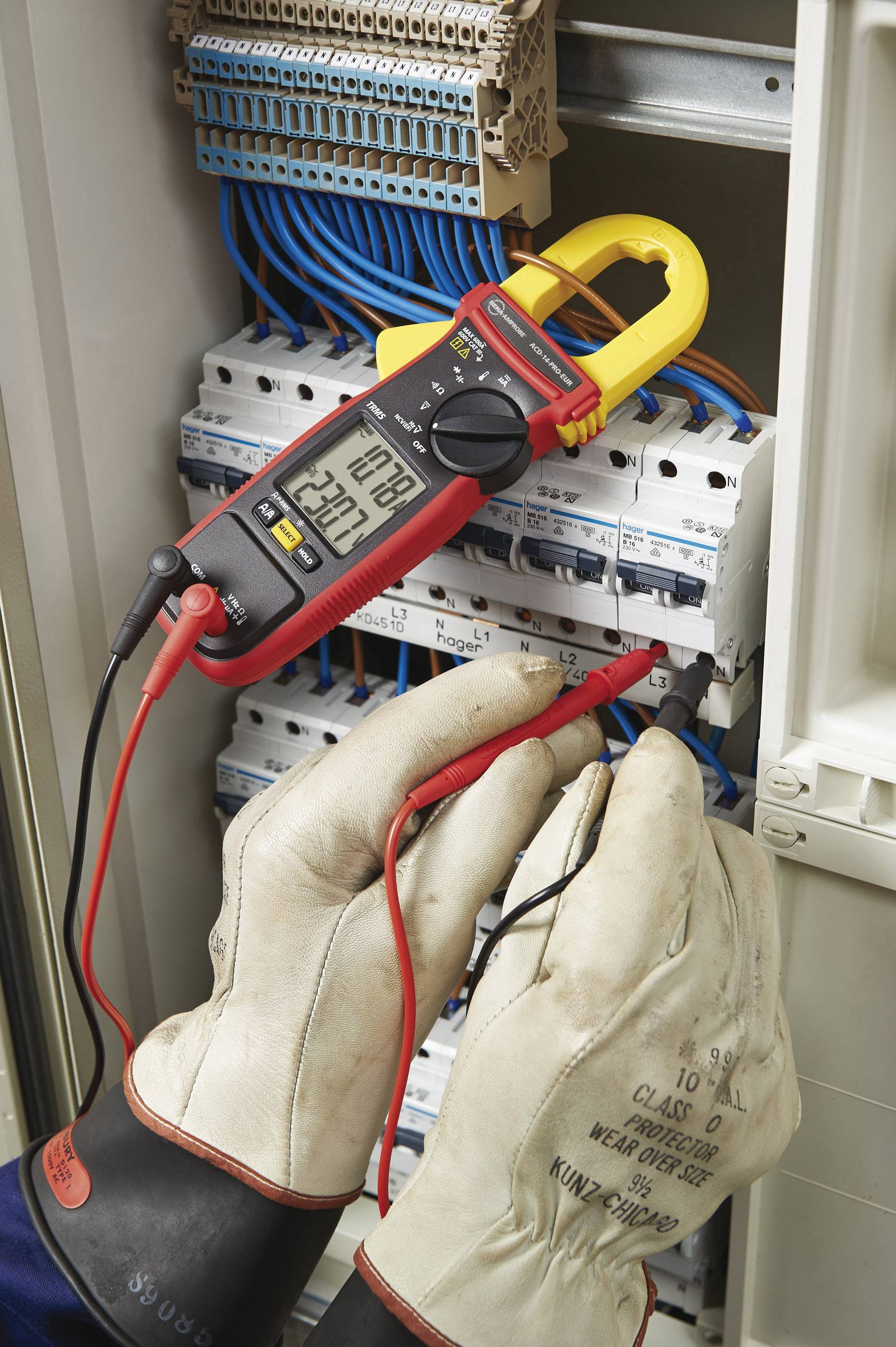 Eine Person mit Schutzhandschuhen misst den elektrischen Strom in einem Schaltschrank mit einem digitalen Multimeter.