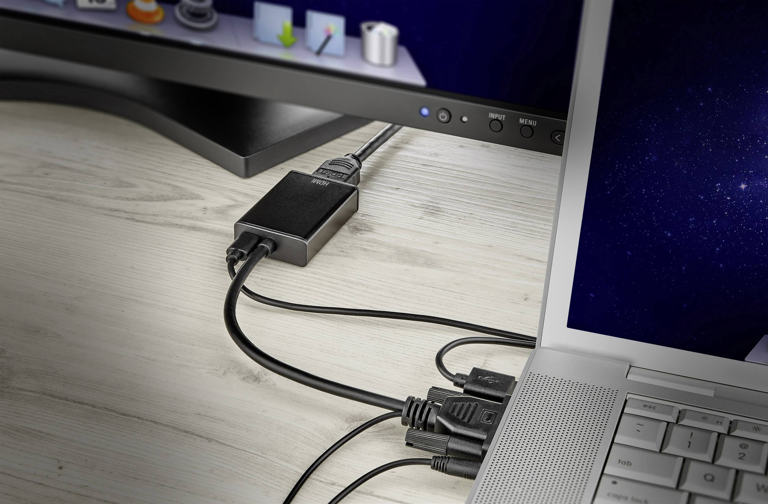 Ein Laptop ist über ein schwarzes Adapterkabel mit einem Monitor verbunden. Auf dem Monitor ist eine Symbolleiste sichtbar.