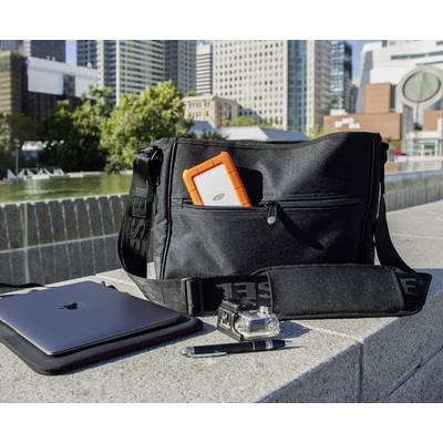 Eine schwarze Tasche mit oranger Festplatte, einem Laptop, einer Kamera und einem Stift in einer städtischen Umgebung im Freien.