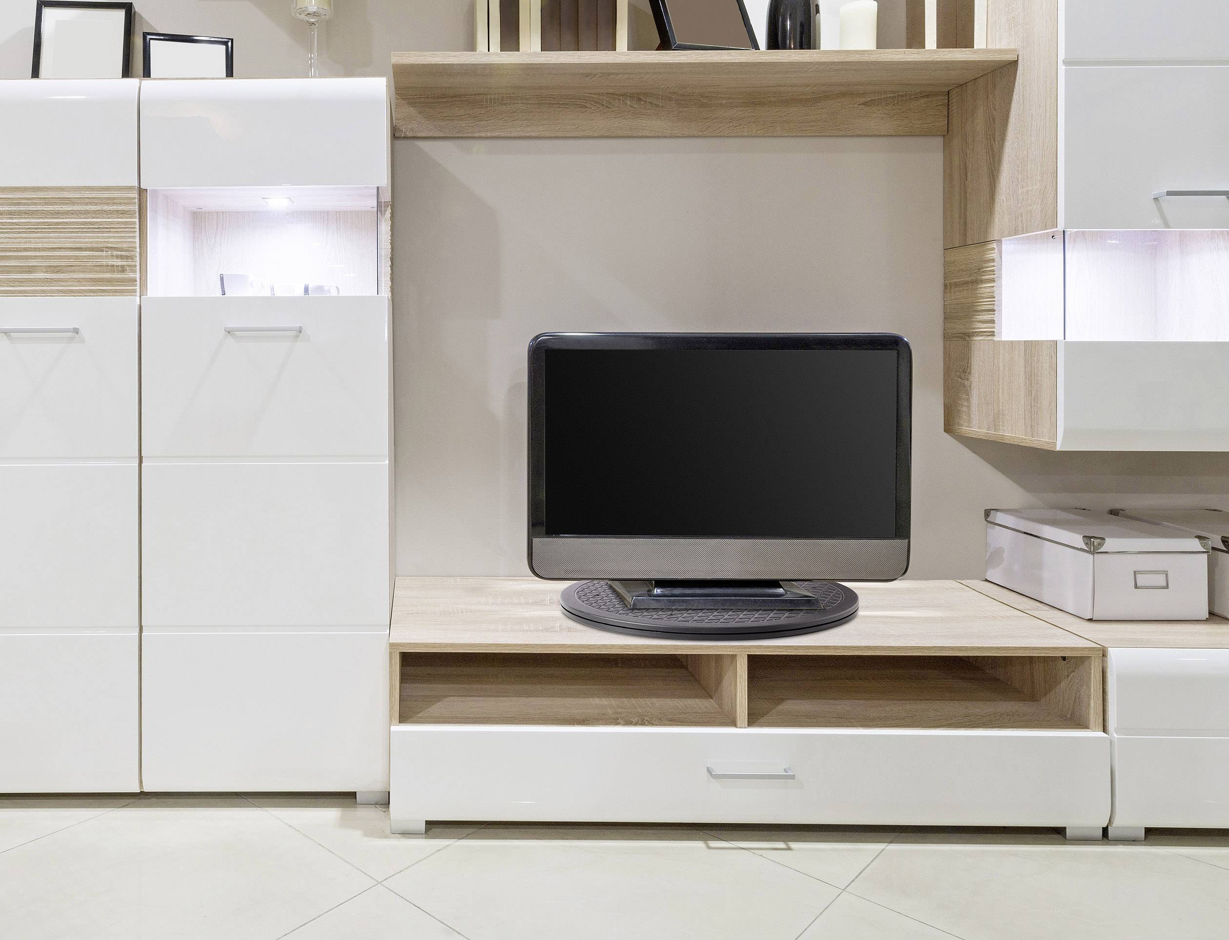 Ein Fernseher mit schwarzem Bildschirm steht auf einem modernen, weißen Wohnzimmerschrank aus Holz mit mehreren Regalen und Schubladen.