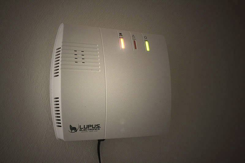 Ein an der Wand montiertes Sicherheitssystem mit zwei leuchtenden Statusanzeigen, eine rot, eine gelb. 