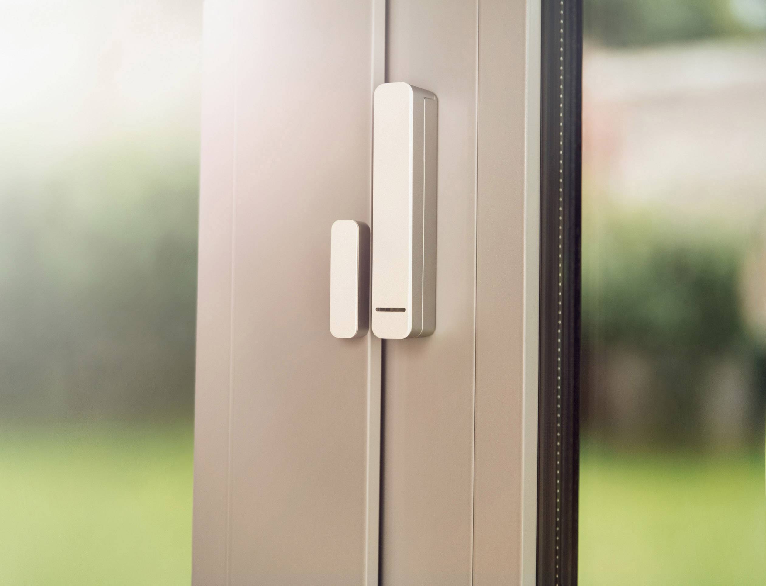 Ein Fenstersensor an einem geschlossenen Fensterrahmen. Der Sensor überwacht geöffnete oder geschlossene Zustände zur Sicherheit.