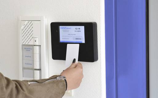 Arbeitszeitbuchung per NFC-fähigem Firmenausweis Das Bild zeigt, wie eine NFC-Karte zur Arbeitszeitbuchung an ein an der Wand montiertes Lesegerät  gehalten wird.