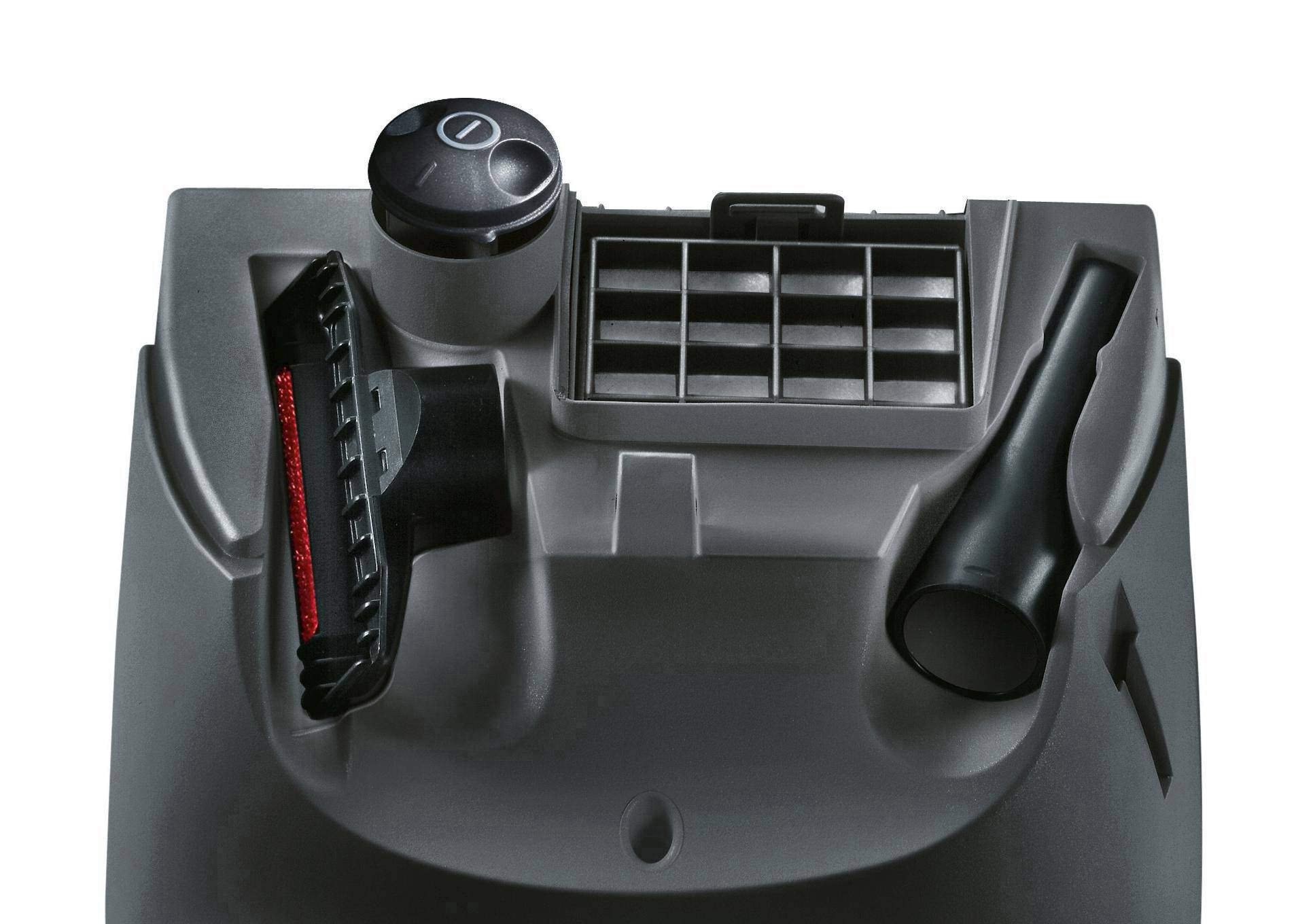 Staubsauger-Zubehör auf einer grauen Oberfläche: eine Bürste mit roten Borsten, ein rundes Drehventil, ein Gitter und eine schmale Düse.