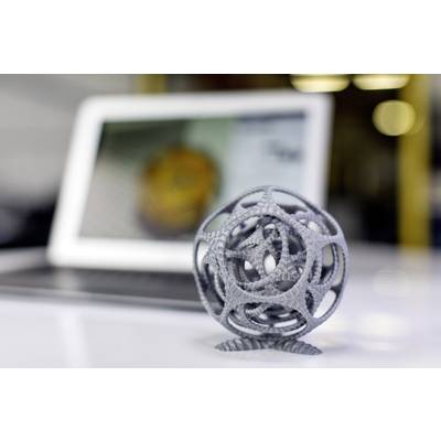 Graues, komplexes 3D-gedrucktes Kugelobjekt im Vordergrund; verschwommener Laptop im Hintergrund zeigt unscharfes Bild.