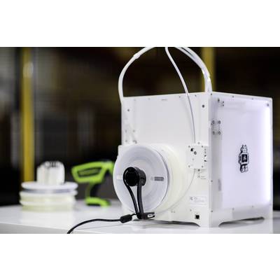 Ein 3D-Drucker mit einer Filamentrolle, im Hintergrund weitere Rollen und ein grünes Werkzeug.