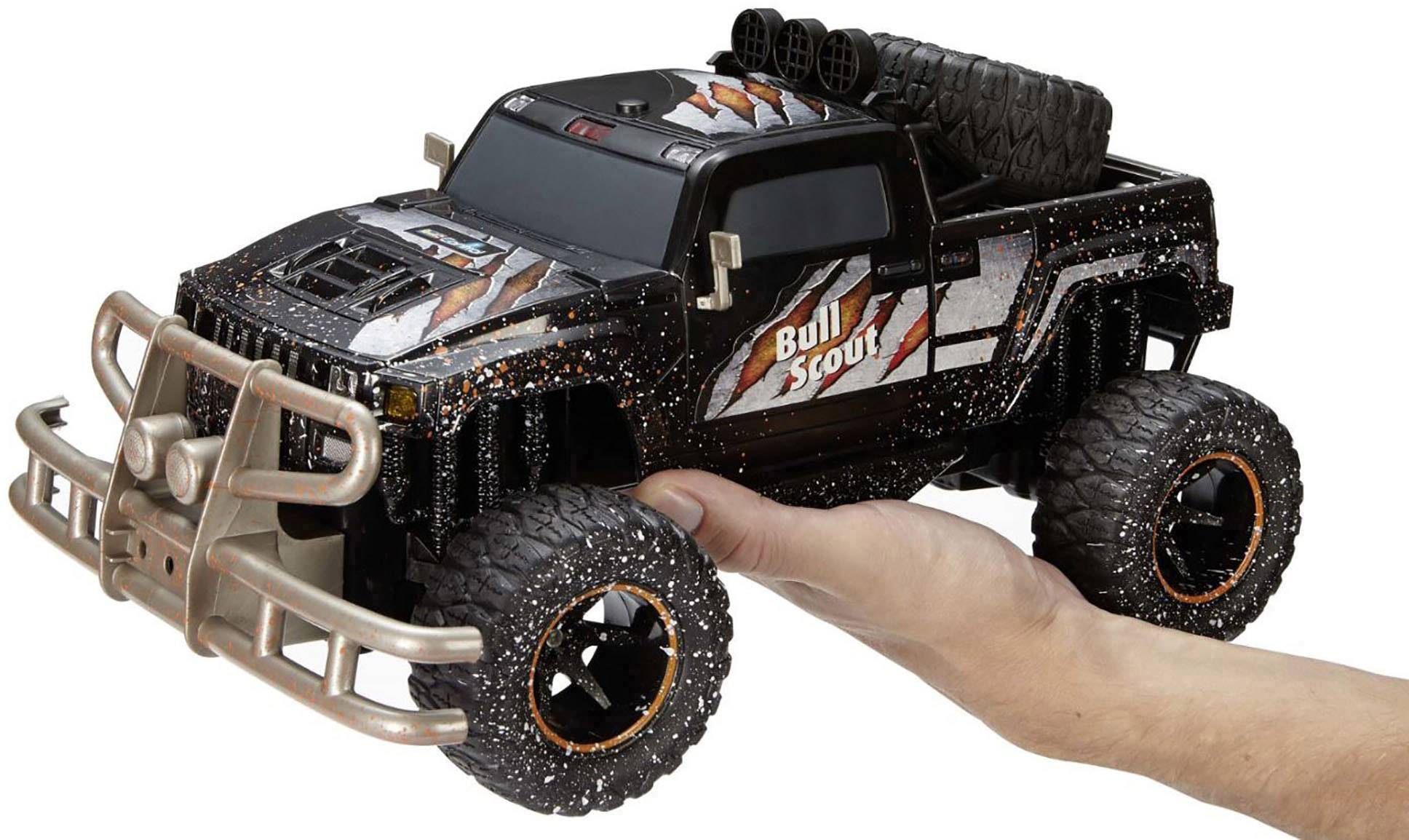 Spielzeug-Monstertruck 'Bull Scout' mit großen Reifen, dunkler Karosserie und Metallic-Akzenten. Wird von einer Hand gehalten.