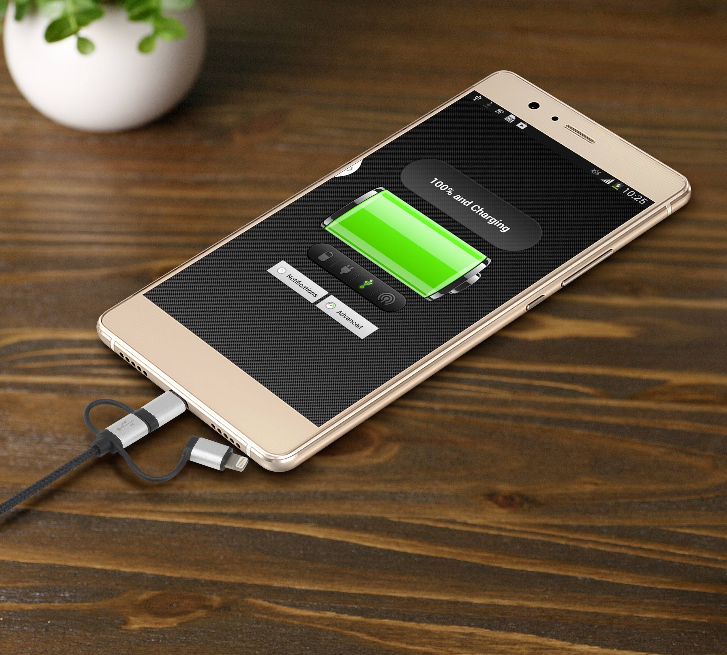 Smartphone auf Holzoberfläche zeigt Ladebildschirm mit 100% Akkustand an, verbunden mit einem Ladekabel. Im Hintergrund eine Pflanze.