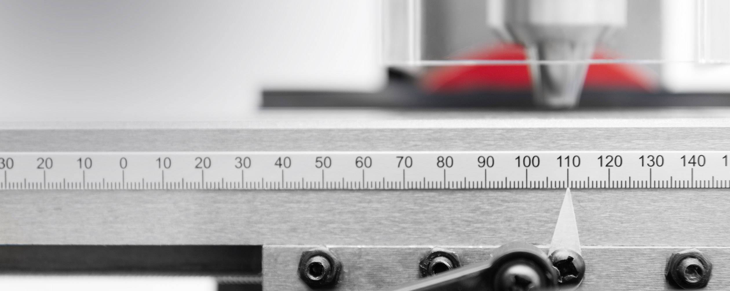 Nahaufnahme eines metallischen Maßstabs mit einer Skala von 80 bis 140 Millimetern. Eine Präzisionsmaschine misst ein Objekt.