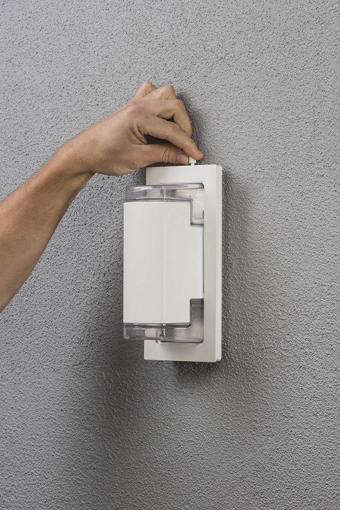 Eine Hand montiert eine moderne, vertikale Außenleuchte an eine graue Wand. Die Lampe hat ein schlichtes, weißes Design.