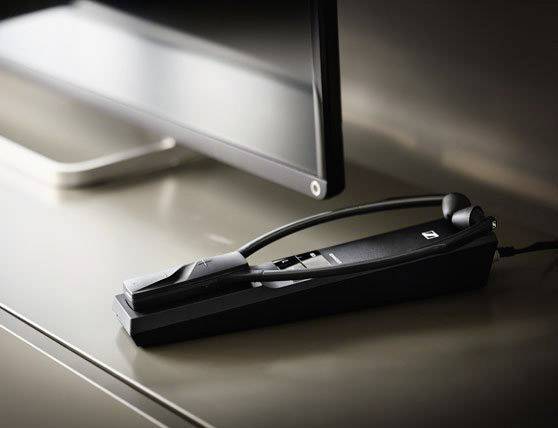 Ein stilvoller Kopfhörer auf einem Tisch neben einem Monitor. Der Kopfhörer ist in einem eleganten, schlichten Design gehalten.