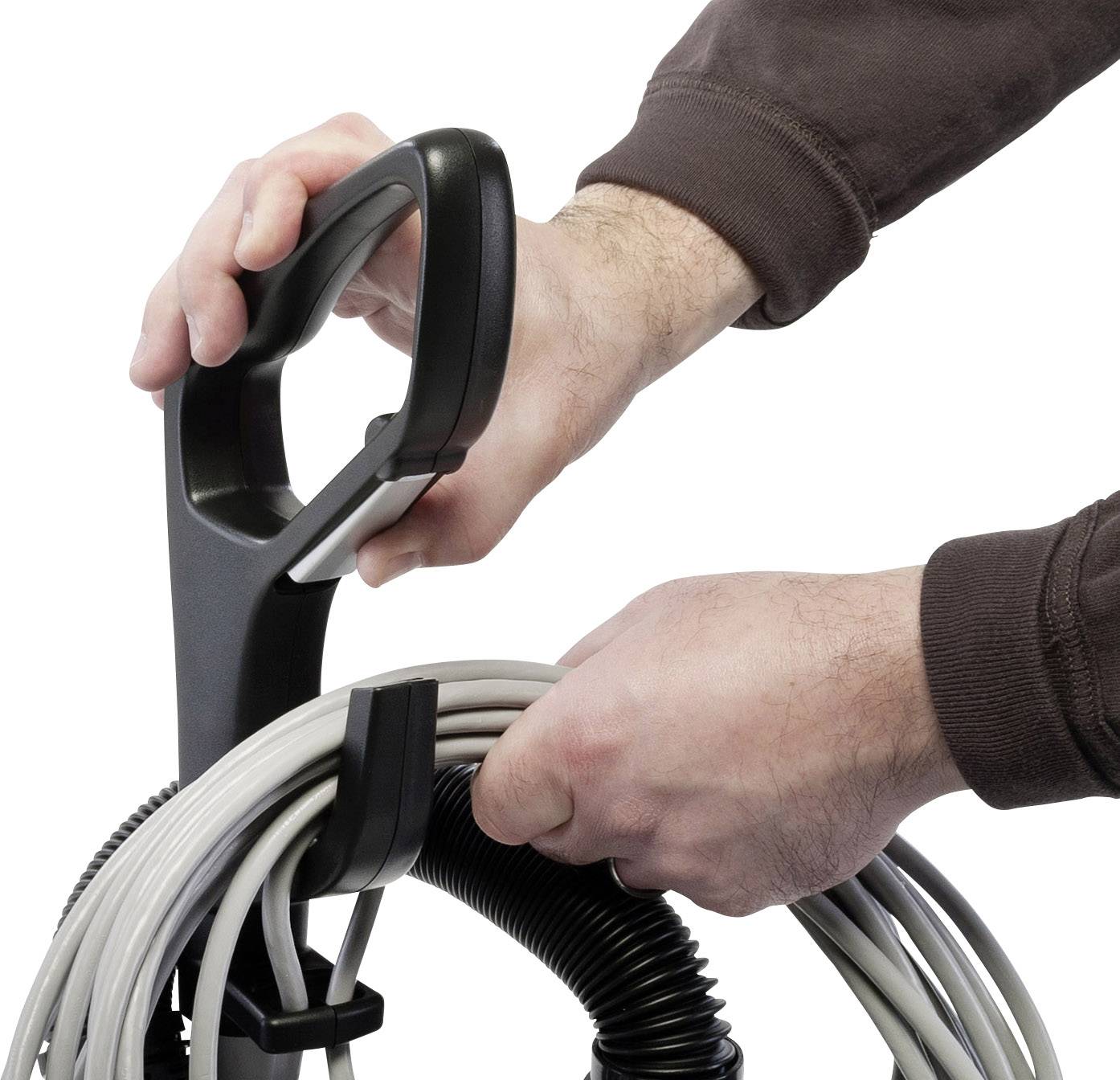 Eine Person hält den Griff eines Staubsaugers, der mit einem aufgewickelten Kabel versehen ist. Hände sichtbar, Fokus auf den Griff.