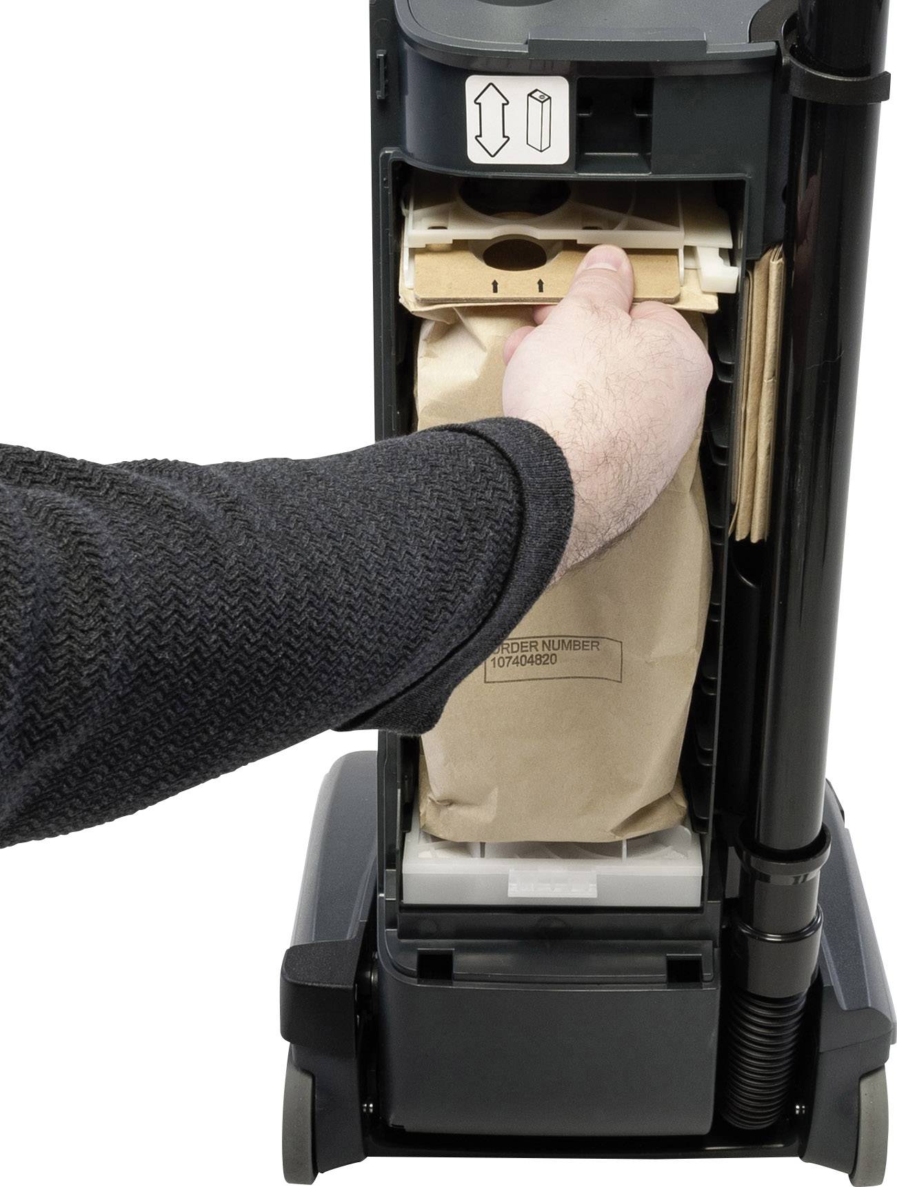 Ein Hand wechselt den Staubbeutel in einem Staubsauger. Der Beutel wird aus einem vertikalen Fach entnommen, bereit für den Austausch.