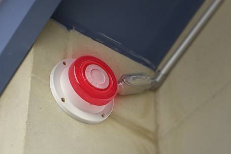 Roter und weißer Alarmmelder an einer Wand montiert.