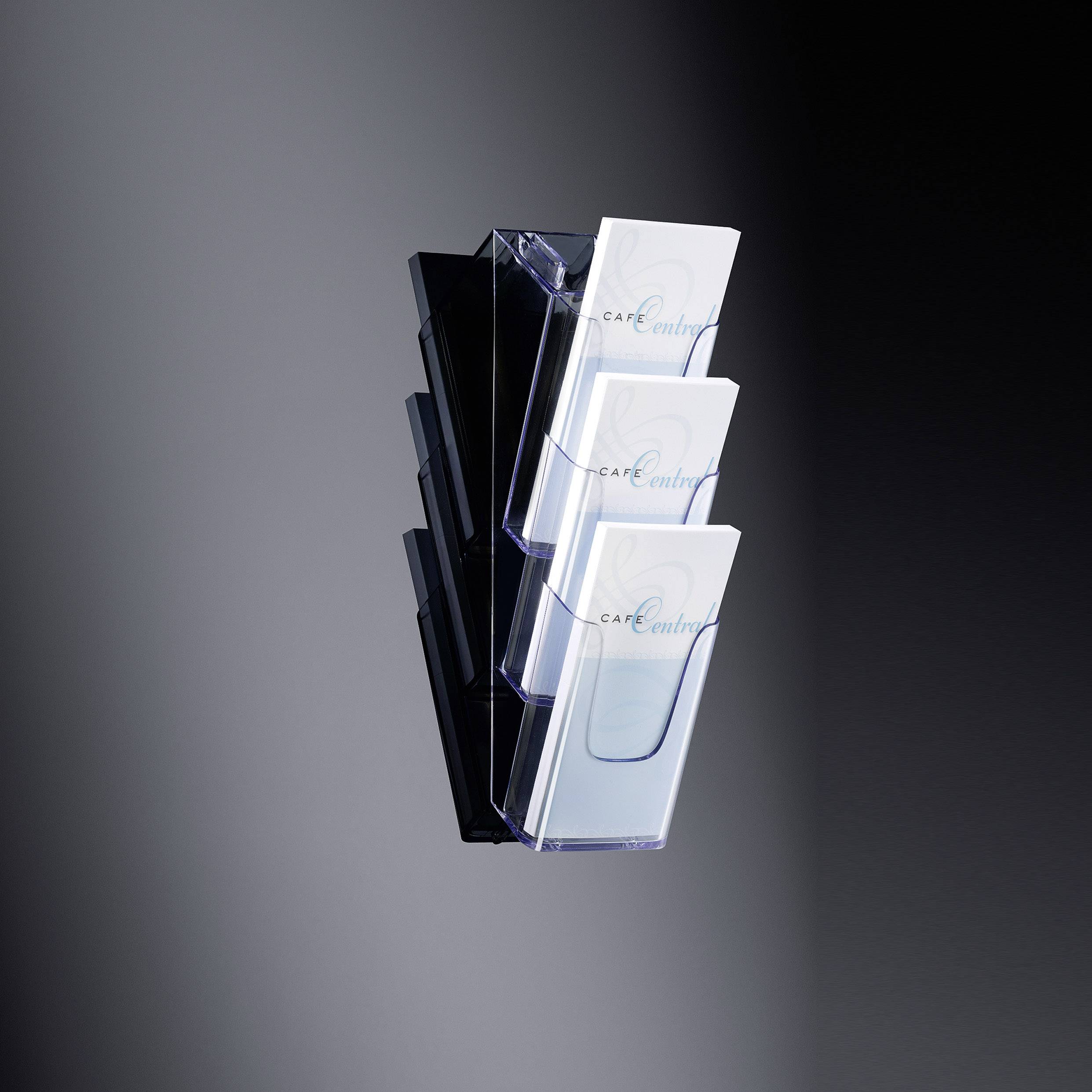 Ein Wandprospekthalter mit mehreren transparenten Fächern, gefüllt mit Broschüren, die 'Café' und 'central' zeigen, vor einem dunklen Hintergrund.