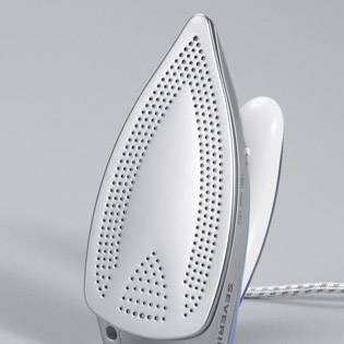 Ein silbernes Bügeleisen mit Dampföffnungen, steht aufrecht, Hintergrund schlicht grau. Hauptmerkmal: Design der Bügelsohle.