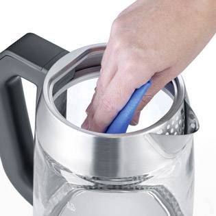 Eine Hand reinigt mit einem blauen Schwamm das Innere eines Wasserkochers. Der Wasserkocher hat einen Stahlrand und einen schwarzen Griff.