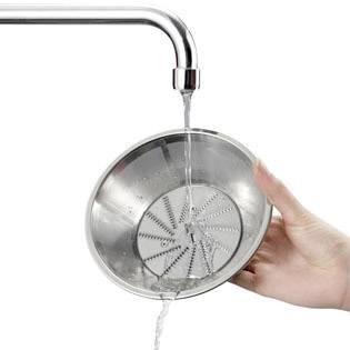 Eine Hand hält ein Metallsieb unter fließendes Wasser aus einem Wasserhahn.