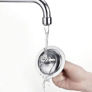 Eine Hand hält einen Löffel unter fließendem Wasser aus einem Wasserhahn, als ob der Löffel gespült wird.