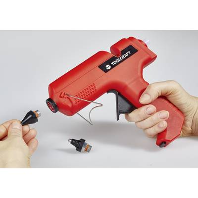 Eine Hand hält eine rote Heißklebepistole, während eine andere Hand eine Düse wechselt.