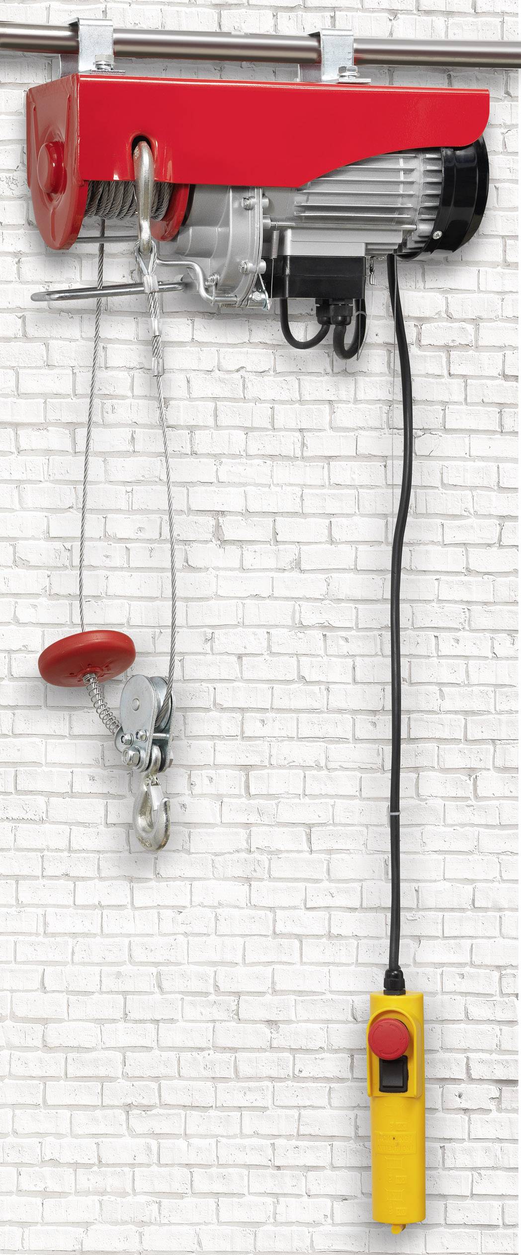 Ein roter elektrischer Seilzug an einer weißen Ziegelwand mit einem gelben Steuergerät.