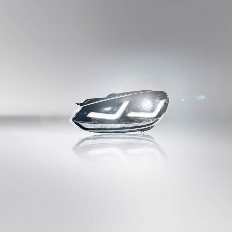 Scheinwerfer eines Fahrzeugs mit moderner LED-Beleuchtung auf grauem Hintergrund. Die Lichter betonen das futuristische Design.