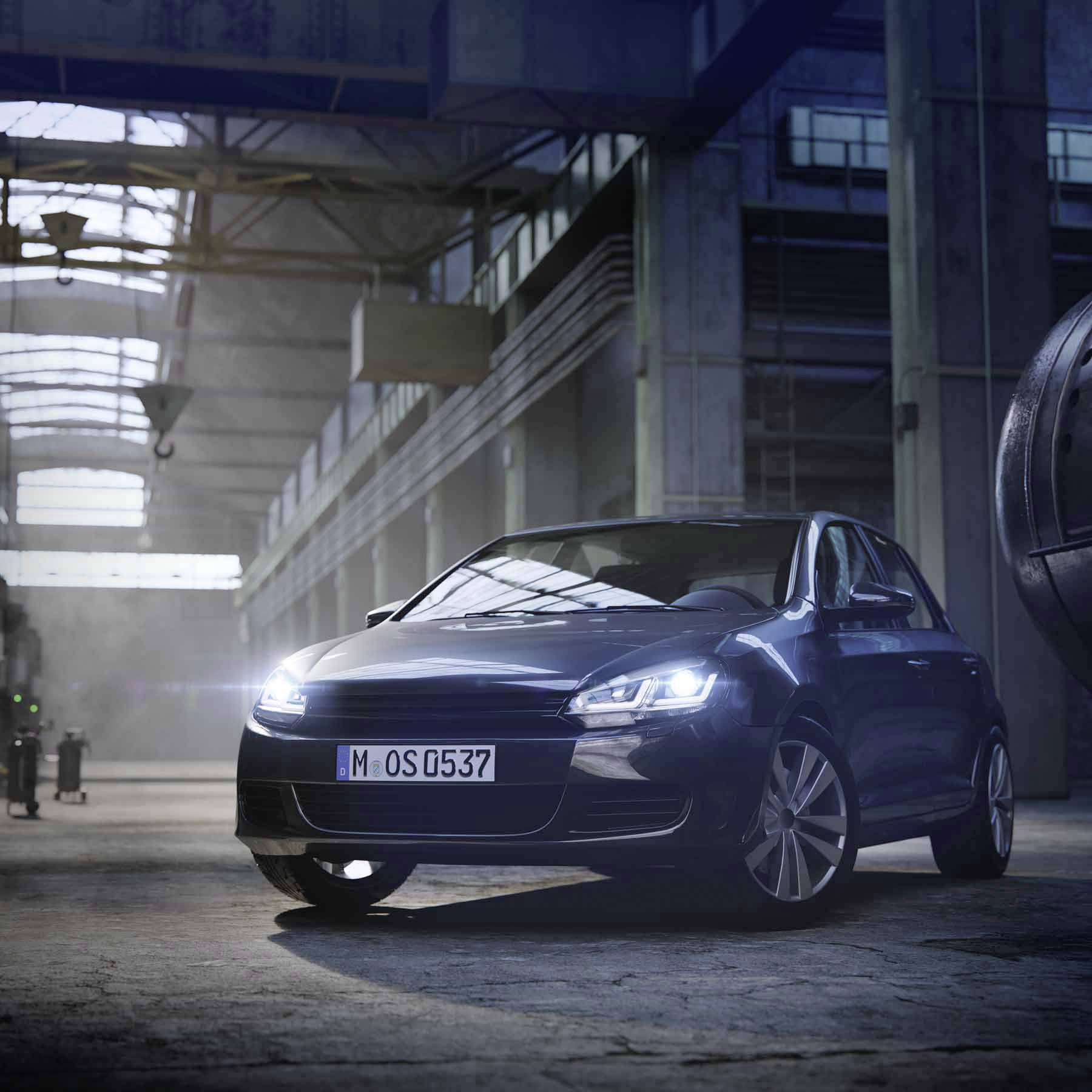 Ein modernes Auto steht in einer industriellen Halle. Die Beleuchtung hebt das Fahrzeug hervor, während das Gebäude im Hintergrund stilvoll wirkt.