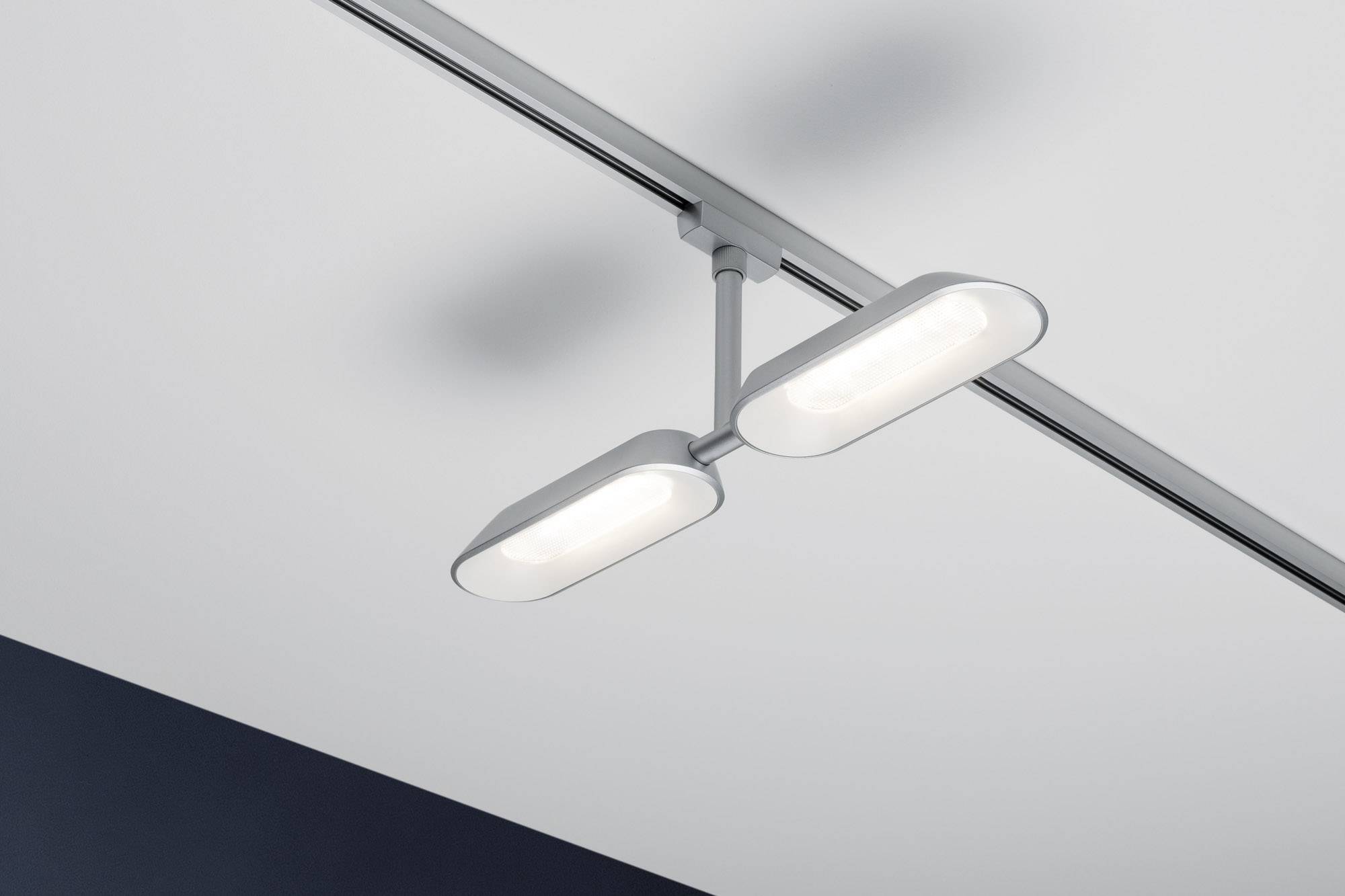 Moderne, rechteckige Deckenleuchte mit zwei flachen, weißen Lampen an einer Schiene, montiert an einer weißen Decke.