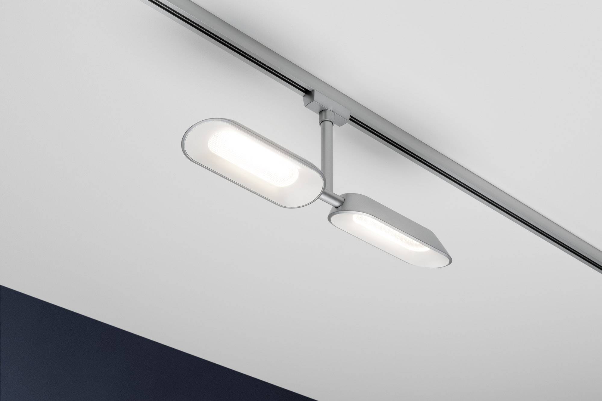 Eine moderne, weiße, längliche Deckenleuchte mit zwei leuchtenden Paneelen an einer grauen Stange auf einer weißen Decke.