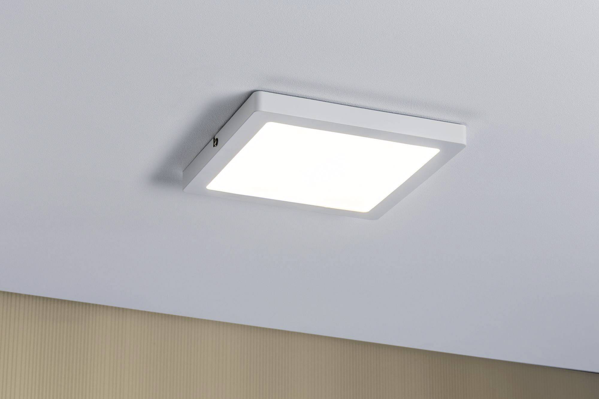 Eine quadratische, weiße LED-Deckenleuchte leuchtet hell an einer grau gestrichenen Decke.
