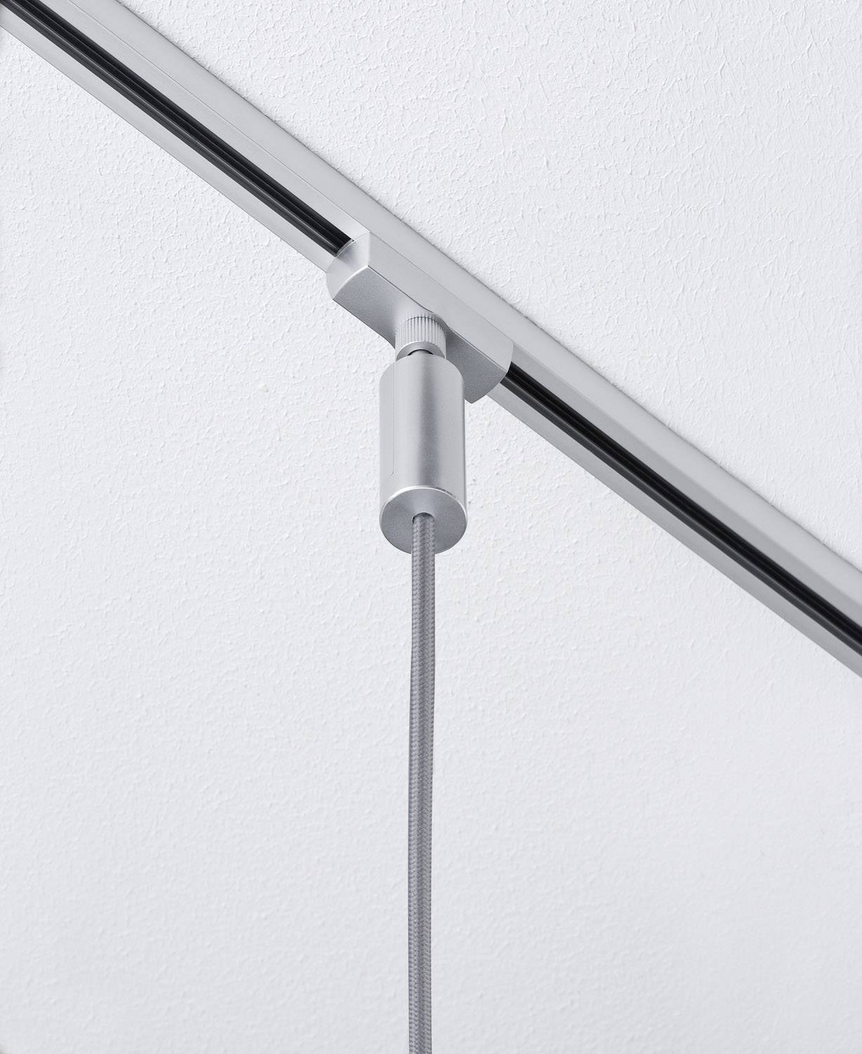 Ein grauer Deckenstrahler mit Kabel ist an einer weißen Schiene an der Decke befestigt, bereit zur Beleuchtung.