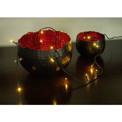 Zwei schwarze, strukturierte Schalen mit rotem Inneren auf einem Tisch, umgeben von leuchtenden Lichterketten.