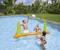 Drei Personen spielen Wasser-Volleyball in einem Pool, umgeben von grünen Bäumen. Ein Mann springt, um den Ball zu schlagen.