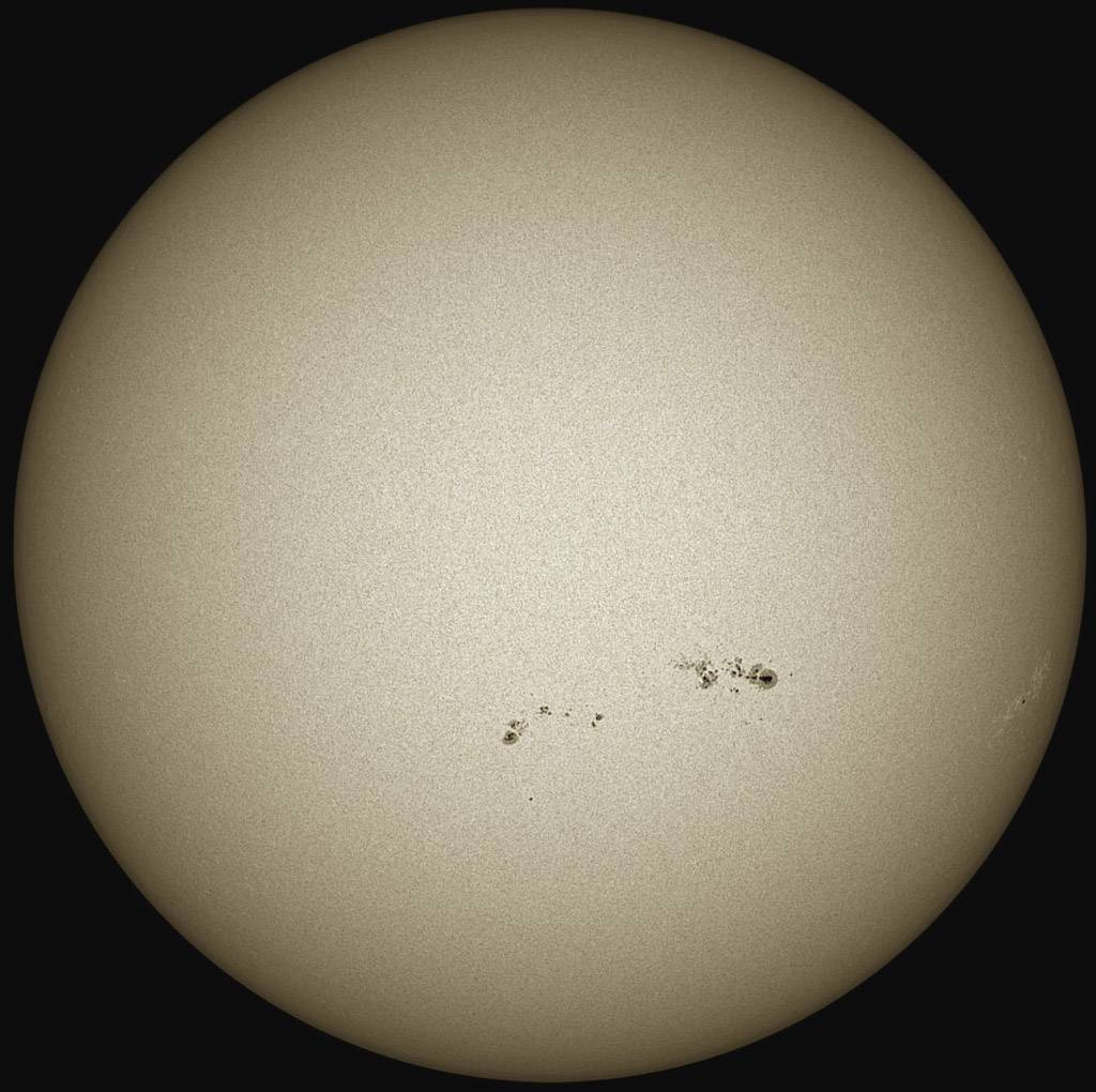 Die Sonne mit einer großen Gruppe von Sonnenflecken auf der Oberfläche, die dunkle Bereiche auf der ansonsten hellen Sonnenscheibe darstellen.