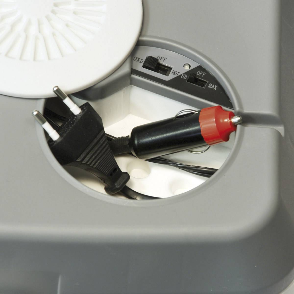 Elektrischer Adapter mit runder Abdeckung und Schalter für Spannungseinstellung. Es sind ein europäischer Stecker und ein Autoadapter sichtbar.