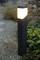 Eine leuchtende Gartenlampe auf einem Kiesweg neben grünen Pflanzen, die Umgebung sanft beleuchtend.