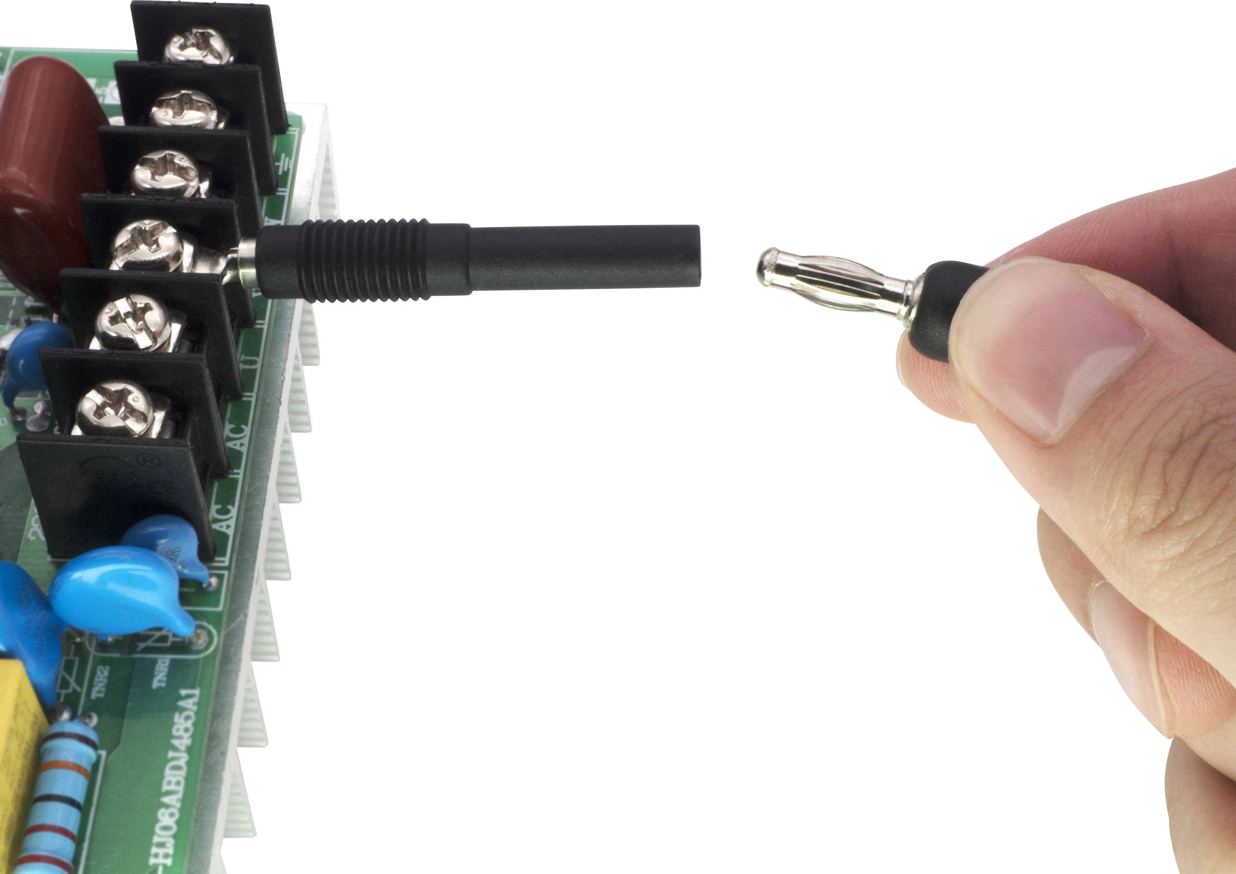 Eine Hand hält einen Stecker, der in eine Buchse auf einer grünen Leiterplatte gesteckt wird, die mehrere Anschlüsse hat.